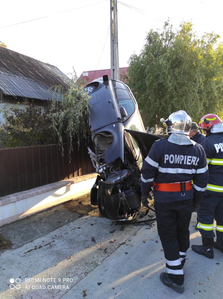 FOTO Șoferița din Țibeni s-a cocoțat cu mașina pe gardul unei case după ce a tras brusc de volan