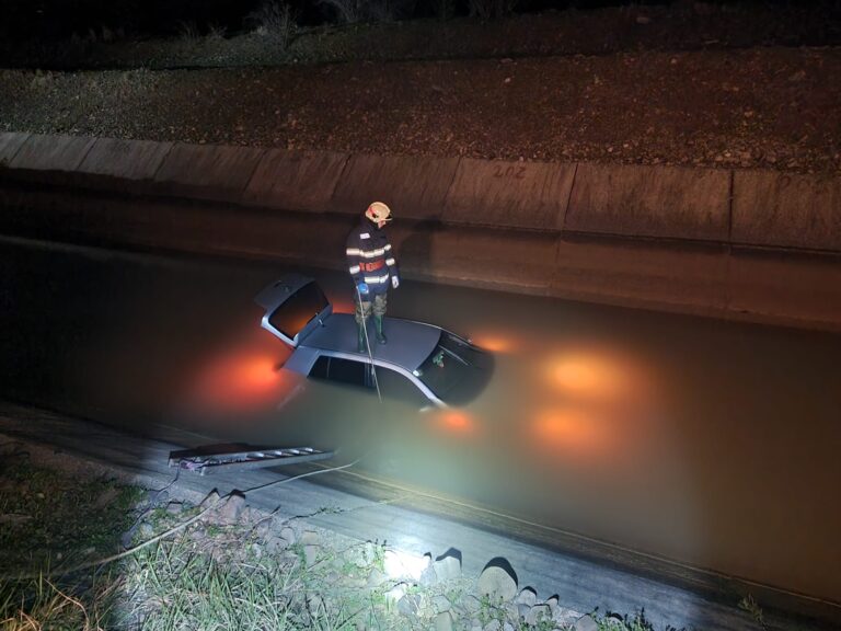 FOTO Un șofer a ajuns cu mașina într-un canal plin cu apă. Tânărul a reușit să iasă singur din vehicul și a fost ajutat de polițiști să ajungă la mal