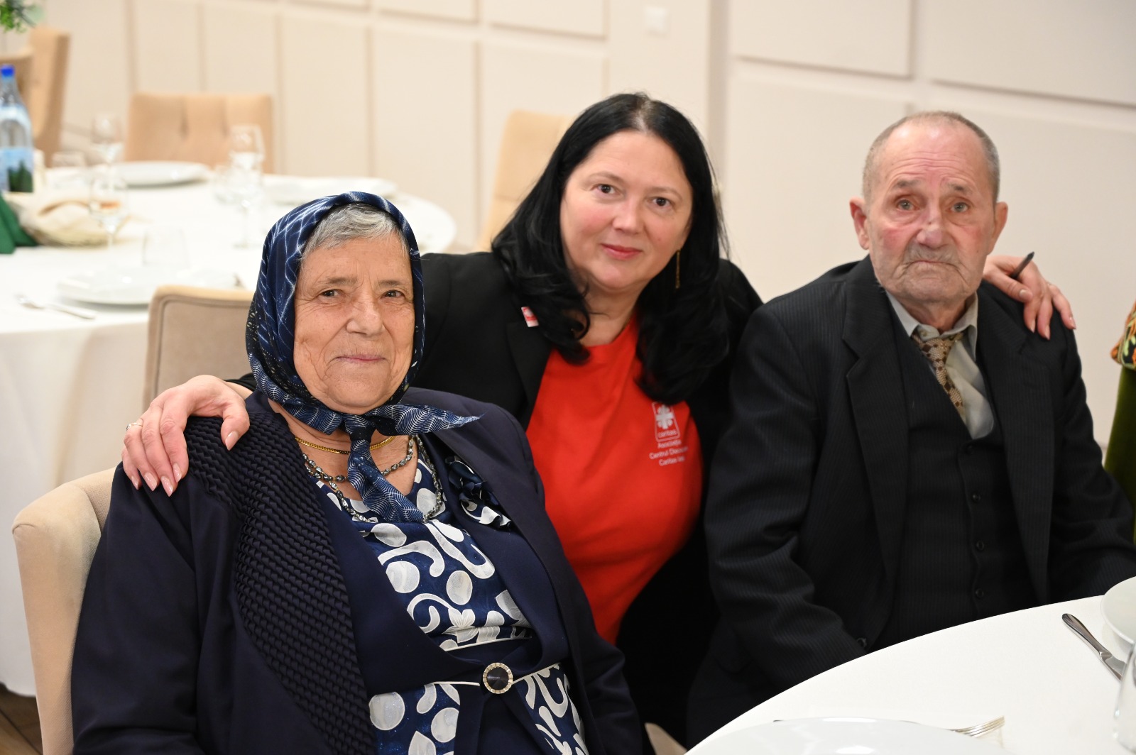 Doi seniori alături de o reprezentantă a Asociației Caritas